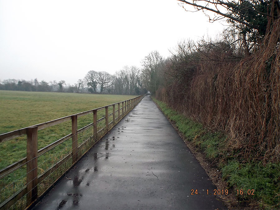 A wide country path, clear of foliage, and freshly tarmacked.