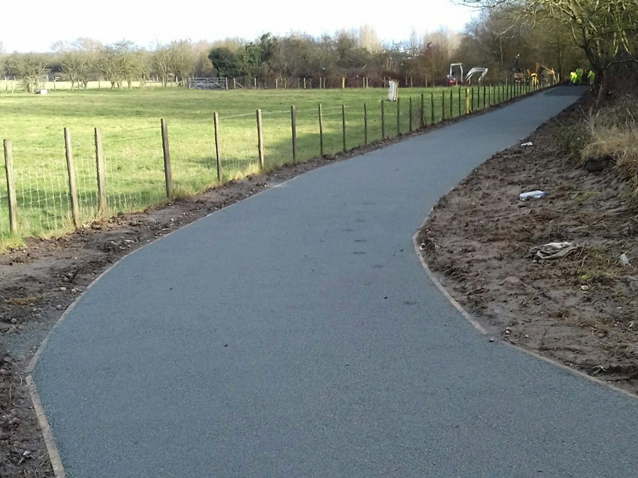 A wide, freshly tarmacked footpath, alongside a field.