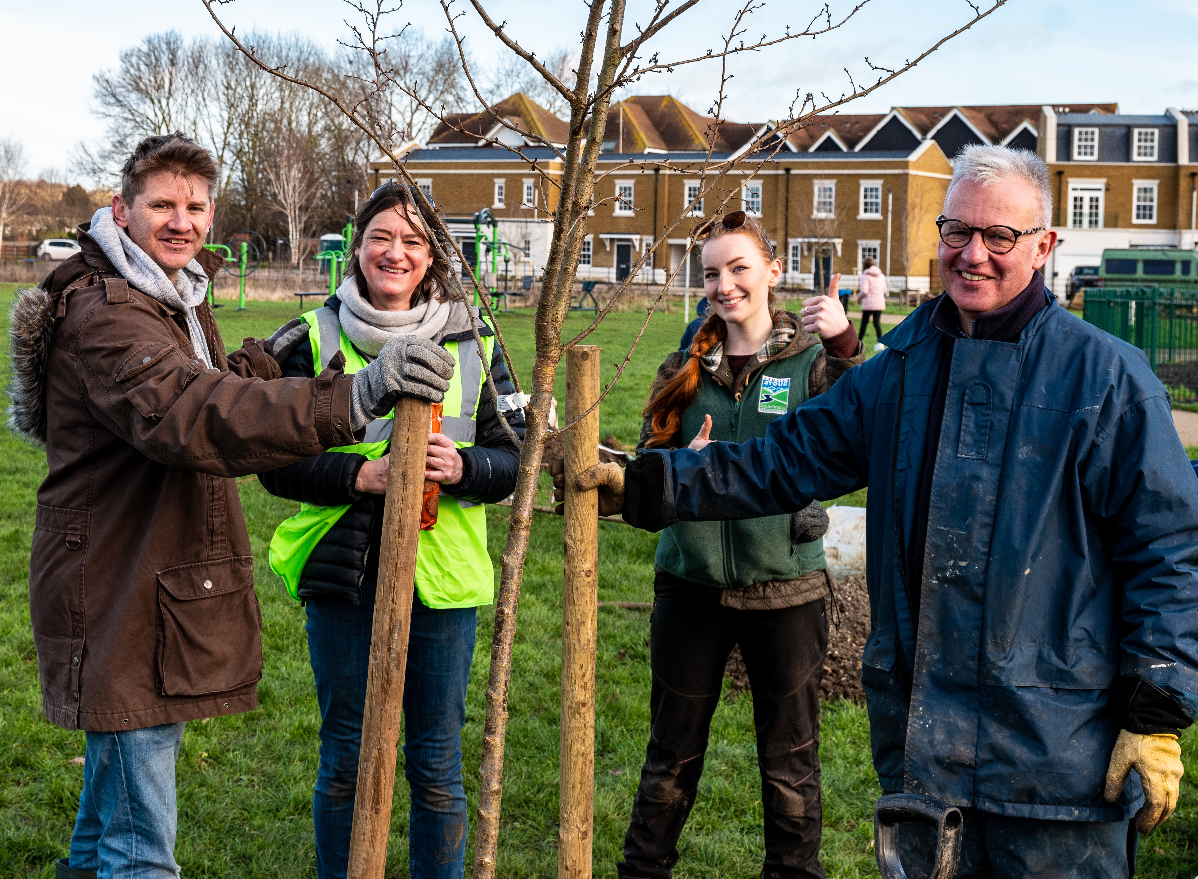 Four people, Alister, Emily, Sian and Jeremy standing around a tree they have just planted.