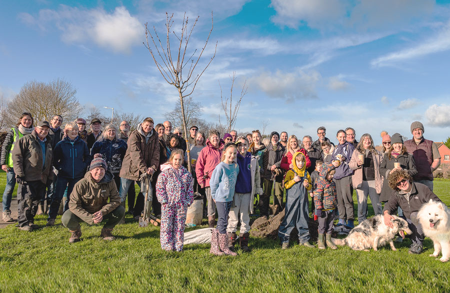 A large group of people, adults and children, in an area where trees are being planted as part of Plan Tree Kent